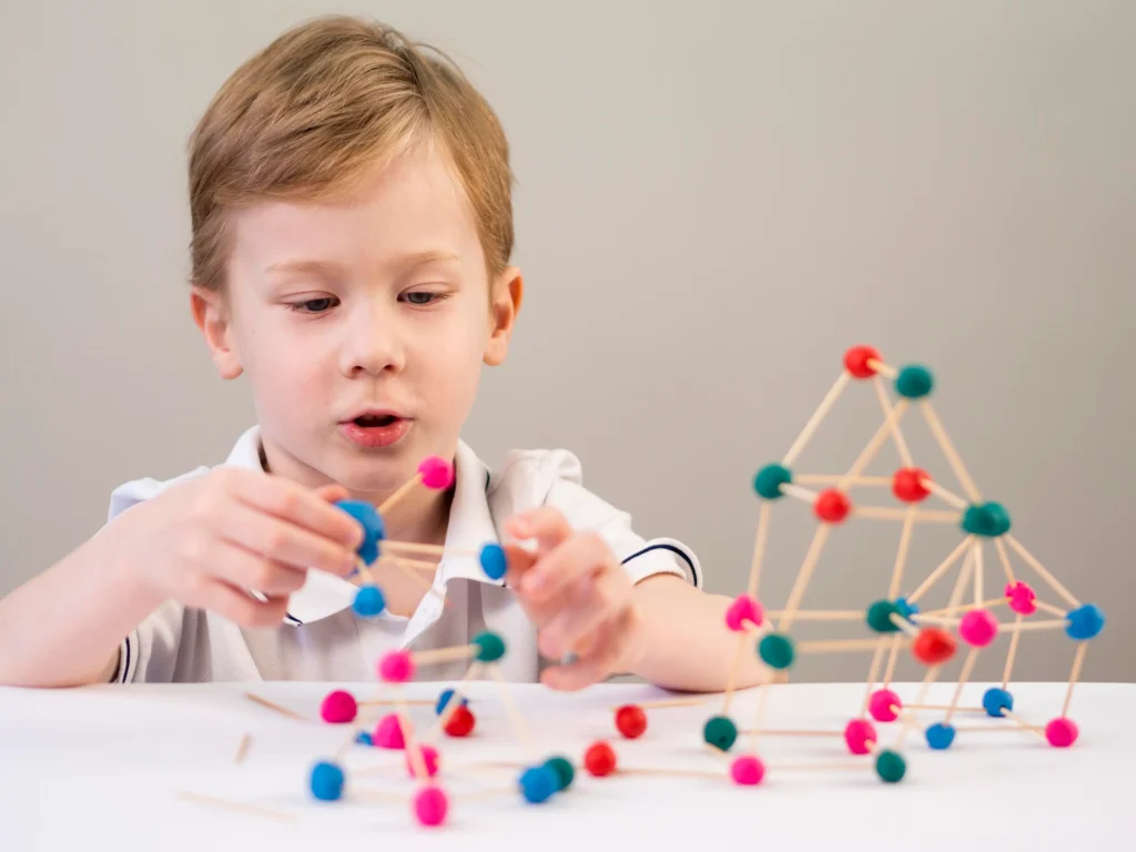 A young boy engages in a hands-on activity, building 3D structures with colorful balls and sticks, promoting creativity and problem-solving