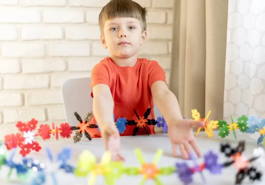 Child engaging in focused play with colorful sensory toys, illustrating early developmental activities related to autism spectrum disorder.