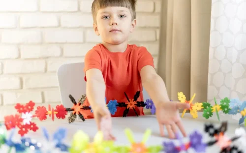 Child engaging in focused play with colorful sensory toys, illustrating early developmental activities related to autism spectrum disorder.