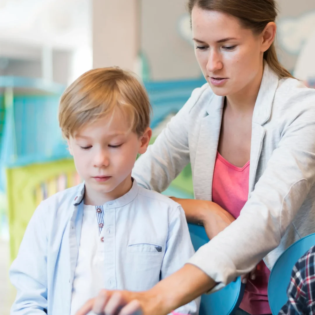 Personalized Special Education Service Support in the Classroom Teacher assisting young boy with a hands-on activity in a classroom, representing special education service support.
