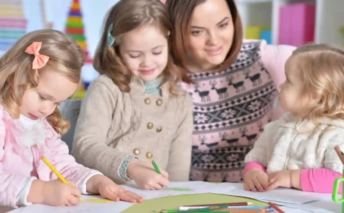 Teacher guiding young children in a classroom activity focused on special needs education and creative learning.