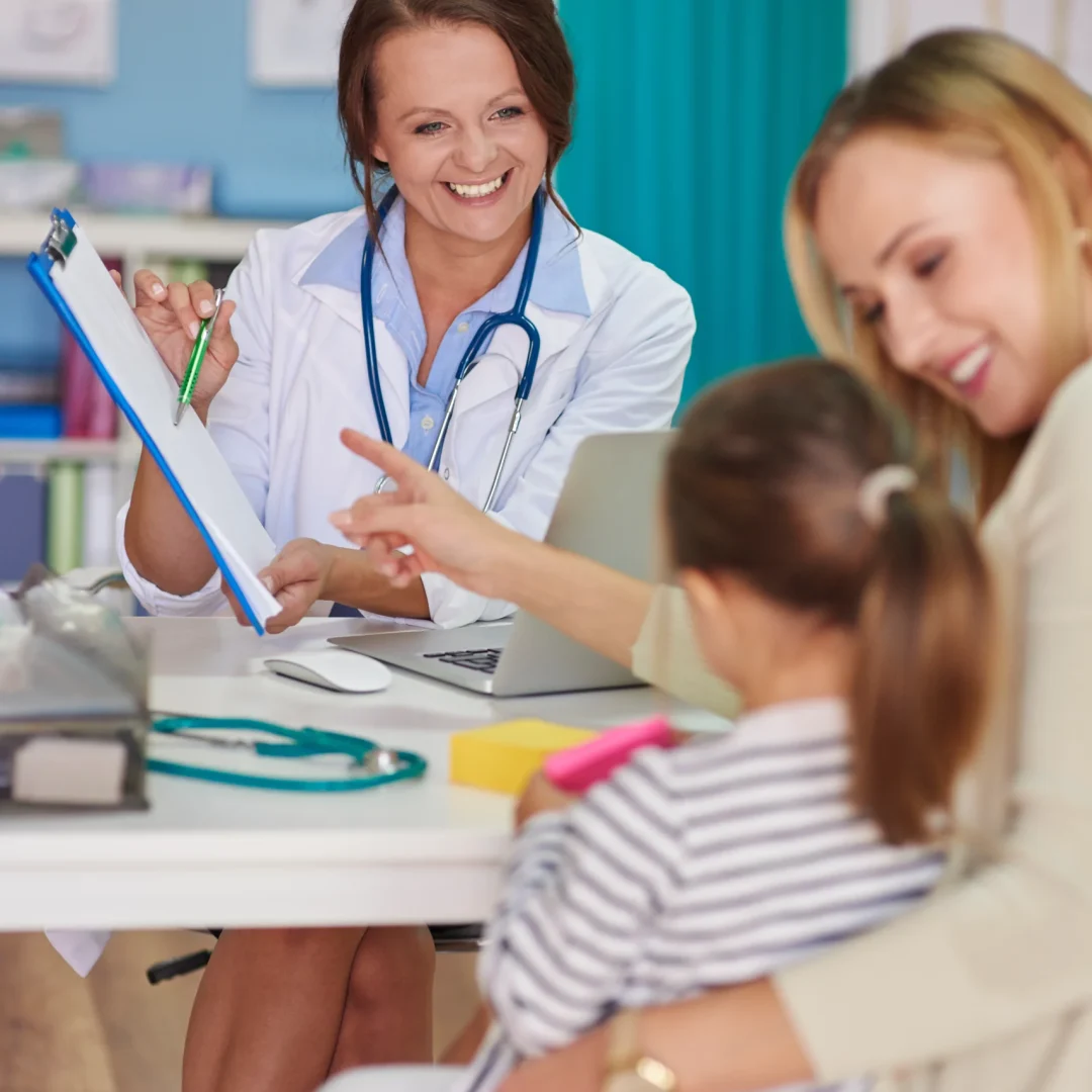 these-are-results-your-examination Smiling clinical psychologist in Kerala showing test results to a mother and her young daughter in a friendly consultation setting.